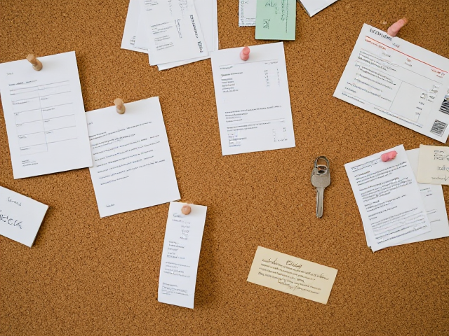 corkboard with random pinned notes, receipts, and keys