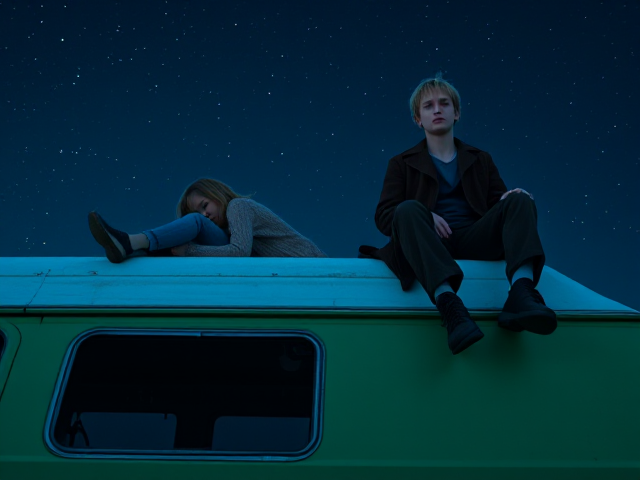 A petite 12-year-old girl with strawberry blonde hair, wearing a cozy pullover and jeans, is lying on the roof of a weathered green 1987 Chevy van. She is on her back, gazing up at the night sky filled with stars. Next to her on the roof of the van, sits a modern-day, pale skinned vampire in his late twenties, with striking blonde hair, dressed in a brown trench coat and jeans. He appears uneasy as he looks downward