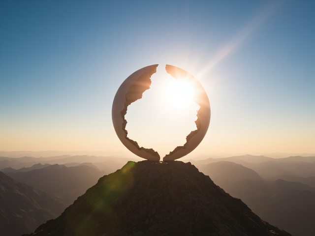 Create an image of a sphere with the main elements cracking open on top of a mountain