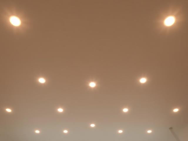 Add small, glowing ceiling lights evenly spaced across the top portion of the background. Each light should emit a soft, warm glow with a slight sparkle effect to make them stand out subtly. The lights should appear embedded into the ceiling structure, with their reflections faintly visible on the surrounding surfaces. Ensure the brightness is balanced so that the lights look natural and do not overpower the central elements. Use varying intensity for some lights to create a realistic effect, mimicking the subtle twinkle and shine of modern ceiling fixtures.