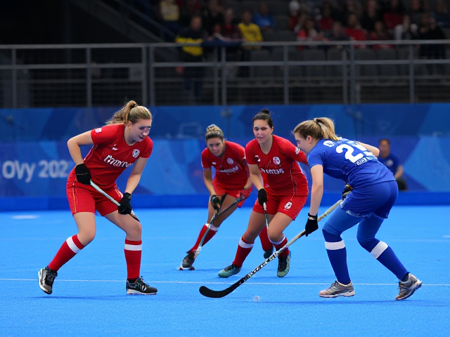 Olympic women’s fiend hockey game between a team in a red uniform and a ream in a blue uniform