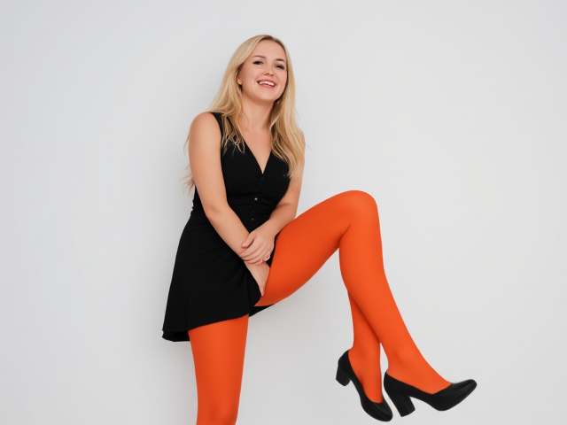 beautiful blonde women in black vest, black mini skirt, orange tights and black heels laughing.  Her full body is visible from head to toe.