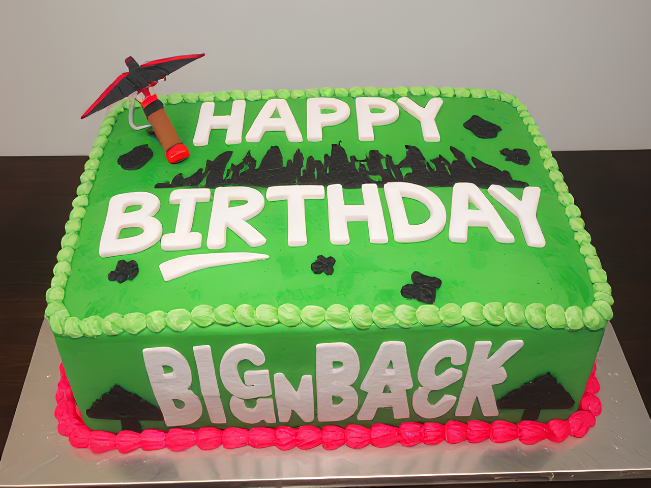 Extremely large fortnite cake that says "happy birthday big back" with Fortnite pickaxe and glider
